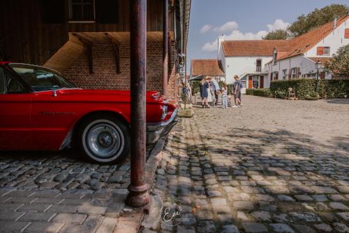 a red car parked on the side of a street at B&B Hullebrug in Heist-op-den-Berg