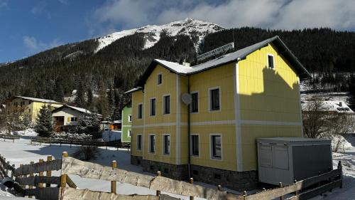 a yellow building with a mountain in the background at House of BaRanGo in Präbichl
