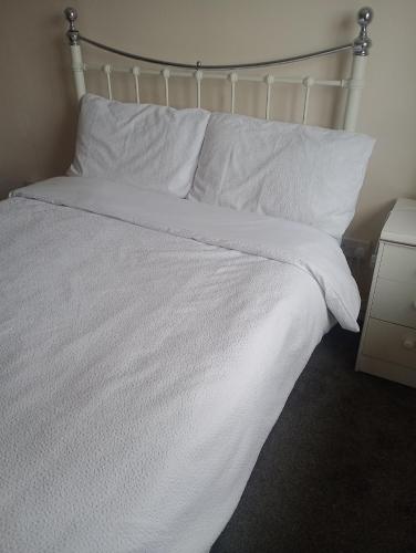 a white bed with white sheets and pillows at Milton Keynes lettings in Milton Keynes