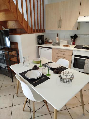 a white kitchen with a white table and chairs at La Ferme de Frévan in Sarceaux
