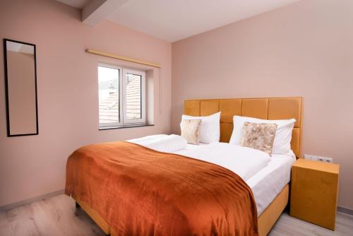 a bedroom with a large bed with an orange blanket at Hotel Parkzicht in Valkenburg