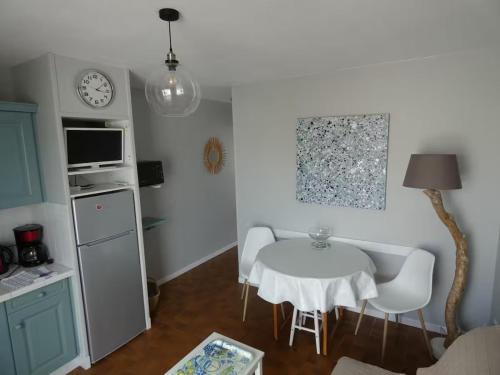 une petite cuisine avec une table et des chaises blanches dans l'établissement Plage des Chalets, à Gruissan