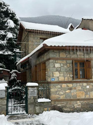 a stone house with snow on top of it at Urban River House in Florina