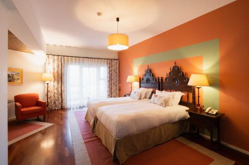 a hotel room with a large bed and a chair at Pousada Valença do Minho in Valença