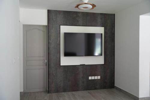 a television on a wall in a room at Villa Orchidée- au coeur du centre-ville in LʼEntre-Deux