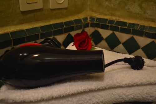 a black hair dryer with a rose on top of towels at Riad Hôtel Belleville Marrakech in Marrakech