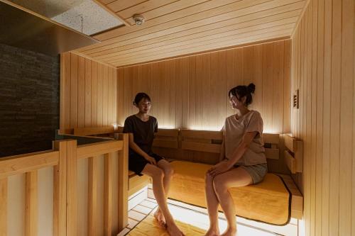 a man and a woman sitting in a sauna at GEMS YUFUIN Hotel and Spa Cafe Bar in Yufuin