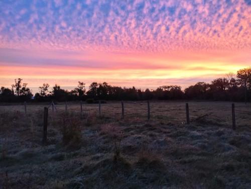 a field with a fence in a field with a sunset at La Ferme de Frévan in Sarceaux