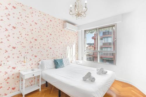 una camera da letto con un letto bianco e fiori rosa di LovelyLoft Mercado ad Alicante