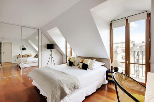 une chambre avec un grand lit blanc et de grandes fenêtres dans l'établissement Prestige Avenue Kléber, à Paris