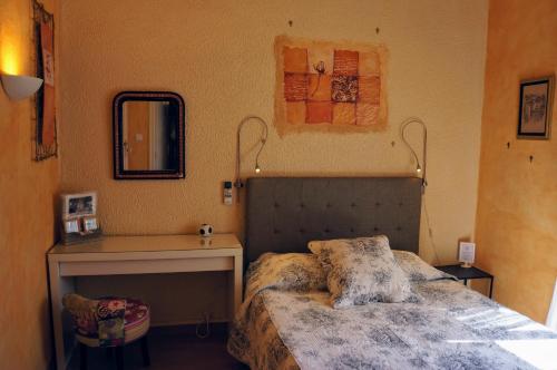 a bedroom with a bed and a table and a mirror at Le Manoir du Raveyron in Vallon-Pont-dʼArc