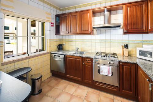 a kitchen with wooden cabinets and stainless steel appliances at 11 Terracos de Benagil - Casa Paraiso in Benagil
