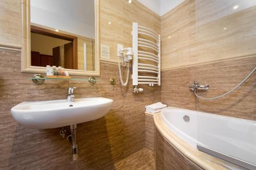 a bathroom with a sink and a mirror and a tub at Ventus Rosa Apartments in Krakow