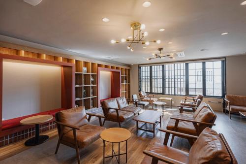 a waiting room with chairs and tables and a projection screen at GEMS YUFUIN Hotel and Spa Cafe Bar in Yufuin