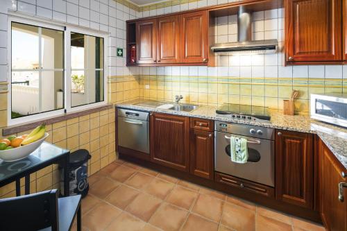 a kitchen with wooden cabinets and a stainless steel oven at 09 Terracos de Benagil - Casa do Pato in Benagil