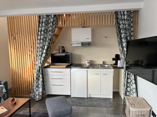 une petite cuisine avec des armoires blanches et un micro-ondes dans l'établissement Petit appartement mitoyen, à Royan