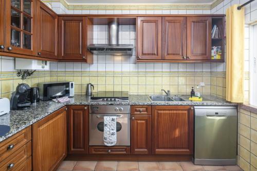 a kitchen with wooden cabinets and a stainless steel dishwasher at 31 Terracos de Benagil - Casa Bobo in Benagil