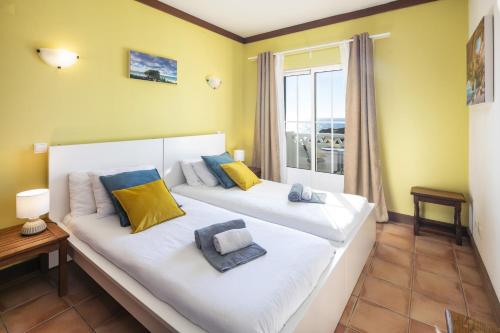 two beds in a room with a window at 31 Terracos de Benagil - Casa Bobo in Benagil