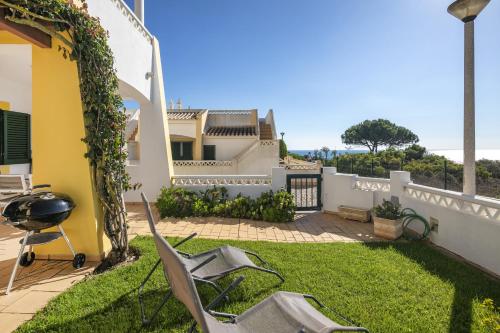 a yard with chairs and a grill and a house at 31 Terracos de Benagil - Casa Bobo in Benagil