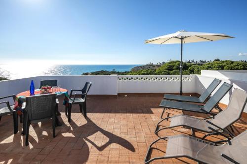 a patio with a table and chairs and an umbrella at 31 Terracos de Benagil - Casa Bobo in Benagil