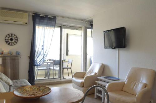 - un salon avec 2 chaises et une télévision murale dans l'établissement Appt 2 pièces cabine 6 couchages CAP D'AGDE CT100-010, au Cap d'Agde