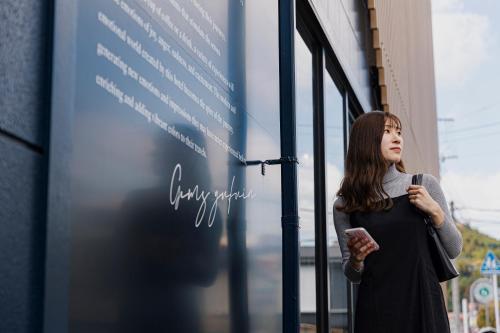 a woman looking out the window of a building at GEMS YUFUIN Hotel and Spa Cafe Bar in Yufuin