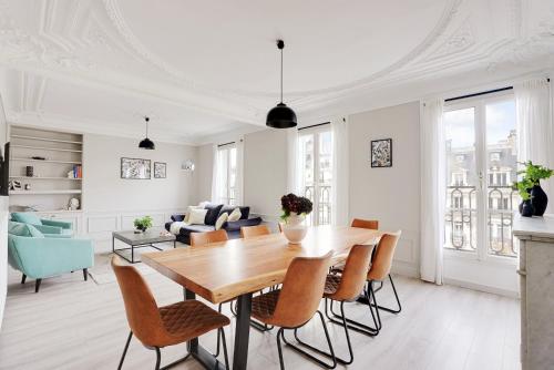 - un salon blanc avec une table et des chaises en bois dans l'établissement Prestige Avenue Kléber, à Paris