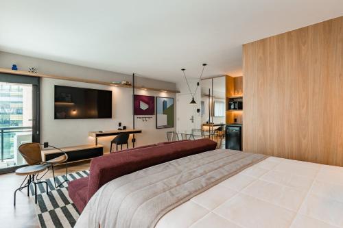a bedroom with a large bed and a living room at Cyclinn Brooklin Novo in São Paulo
