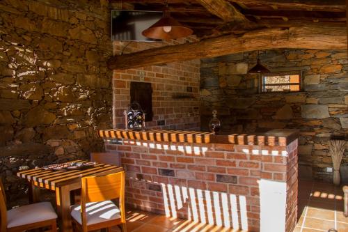 a room with a table and a brick wall at Refúgios do Pinhal in Oleiros