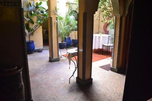 a hallway with a table and potted plants at Riad Hôtel Belleville Marrakech in Marrakech