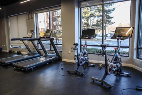 a gym with treadmills and ellipticals in front of windows at Luxury apartment with gym, steps from commuter rail #4011 in Reading