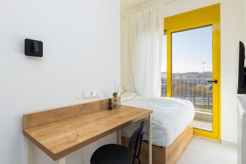 a bedroom with a bed and a desk with a window at Soho Harbor by halu! in Thessaloniki