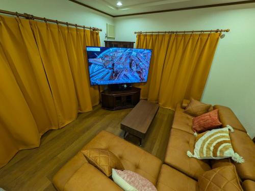 a living room with a couch and a flat screen tv at Villa Tojinbo ヴィラ東尋坊 1棟貸切10人 東尋坊5分 芝政15分 恐竜博物館55分 かに in Sakai