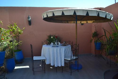 a table with a white tablecloth and chairs and a umbrella at Riad Hôtel Belleville Marrakech in Marrakech
