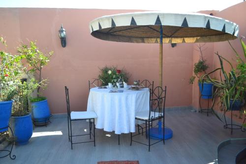 a table with a white tablecloth and chairs in a patio at Riad Hôtel Belleville Marrakech in Marrakech
