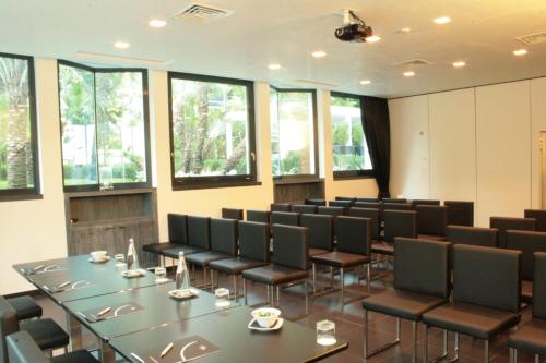 a conference room with tables and chairs and windows at LHP Hotel Montecatini Palace & SPA in Montecatini Terme