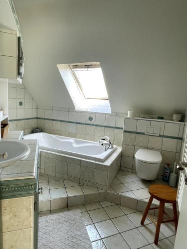 a bathroom with a tub and a toilet and a skylight at Pont-Aven Breton house in Pont-Aven