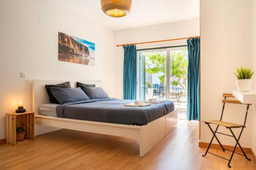 a bedroom with a bed with blue sheets and a window at Kichershome in Sagres