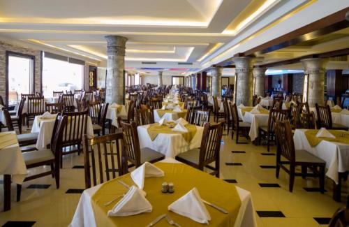 a restaurant with white tables and chairs with yellow napkins at Hurghada Mirage Bay Hotel & Aquapark in Hurghada
