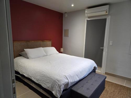 - une chambre avec un grand lit blanc et un mur rouge dans l'établissement Le Cottage des Vignes, à Saint-Christophe-des-Bardes