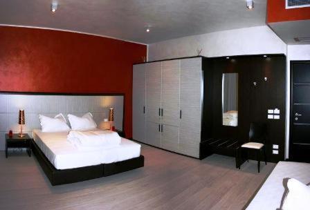 1 dormitorio con cama blanca y pared roja en La Casa Degli Angeli - Agli Angeli Ristorante Pizzeria, en Pertegada