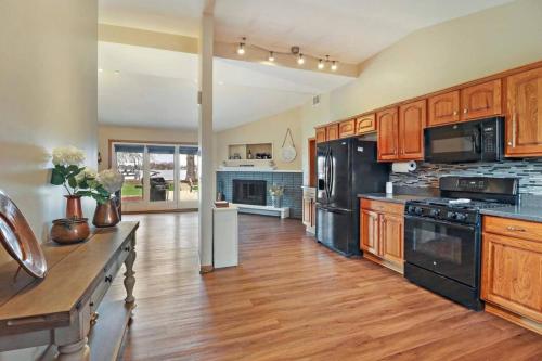 una grande cucina con armadietti in legno ed elettrodomestici neri di Meyers Bay Sunset Lakefront Cottage in Fox Lake with Boat Pier a Fox Lake