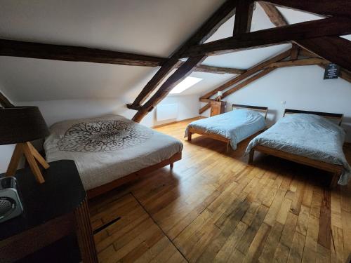 Cette chambre mansardée comprend deux lits et une chaise. dans l'établissement Gîte en Dordogne chez les Couz 'hôtes du Périgord, à Couze-et-Saint-Front