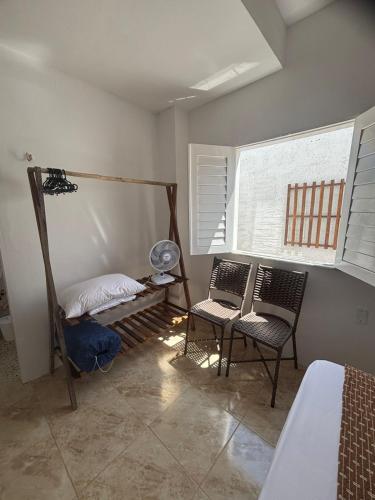 a bedroom with a bed and two chairs and a window at Refúgio da Major in Aracati