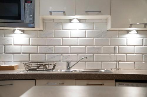 a kitchen with a sink and white tiled wall at NEW! 2BR in Stephenson House in Stockton-on-Tees