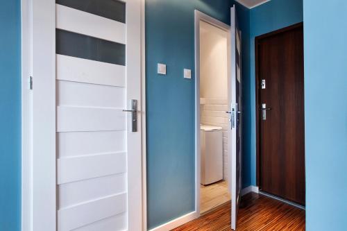 a bedroom with blue walls and white doors at Apartament Blisko Morza Gdańsk in Gdańsk