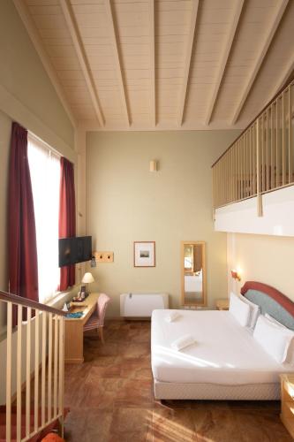 a bedroom with a large white bed and a staircase at Hotel Belvedere San Gottardo by LVG Hotel Collection in Verbania
