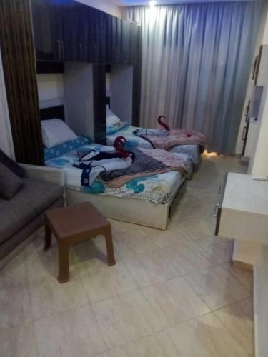 two beds in a room with a couch and a table at Elite apartment private beach Holiday Chalet Free WIFI in Hurghada