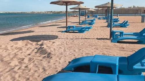 a row of blue chairs and umbrellas on a beach at Elite apartment private beach Holiday Chalet Free WIFI in Hurghada