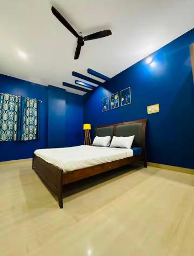 a blue bedroom with a bed with a ceiling fan at Deluxe Rooms near Tree Park Metro station Whitefield in Bengaluru